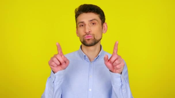 Sweet young man in light blue shirt draws a heart in the air with his fingers — Stock videók