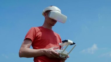 Adam bir kuadrokopteri uzaktan kumandayla kontrol ediyor.