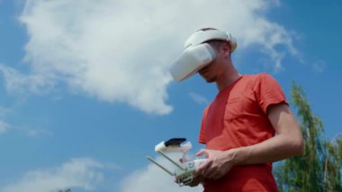 Adam bir kuadrokopteri uzaktan kumandayla kontrol ediyor.