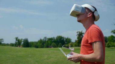 Adam bir kuadrokopteri uzaktan kumandayla kontrol ediyor.