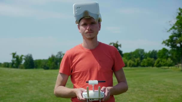 Man in goggles for a quadrocopter and with remote control in his hands — Stock Video