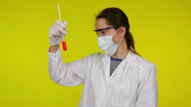 Kadın test tüpünün içeriğini inceliyor ve orta parmağını gösteriyor.