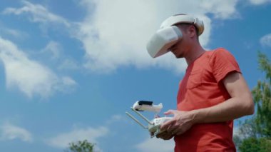 Adam bir kuadrokopteri uzaktan kumandayla kontrol ediyor.