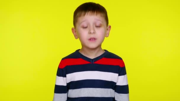 Ragazzo bambino serio in un maglione colorato dice sì su uno sfondo giallo — Video Stock