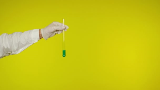 Ruka v latexové rukavici ochrana ukazuje skleněnou trubici se zelenou látkou — Stock video