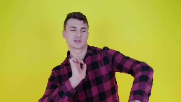 Veselý muž v růžové kostkované košili tančí a usmívá se na žlutém pozadí — Stock video