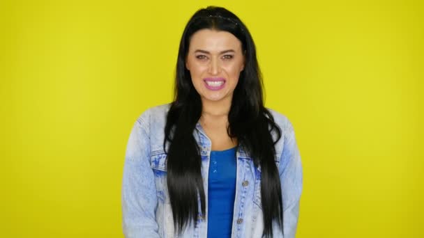 Wütende Frau in Jeansjacke knurrt auf gelbem Hintergrund mit Kopierraum — Stockvideo