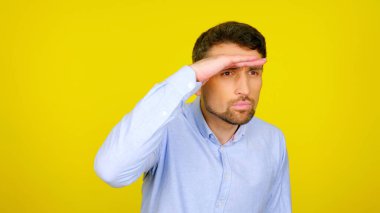 İnsan, elleri alnına dönük bir şekilde, kopyalanmış sarı bir arka plana bakar.