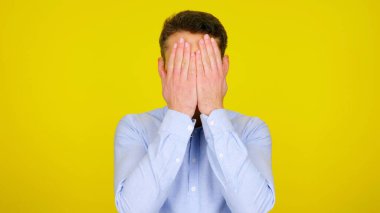 Adam ellerini, kopyalanmış sarı arka planda tutarak yüzünü kapatmış.