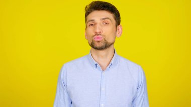 Sarı arka planda yakışıklı sakallı bir adam öpüşüyor.