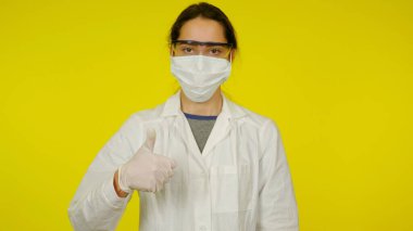 Koruyucu tıp maskeli, gözlüklü, lateks eldivenli genç doktor...