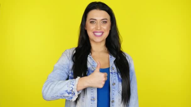 Kvinna visar som, ler och blinkar ett öga på en gul bakgrund med copyspace — Stockvideo