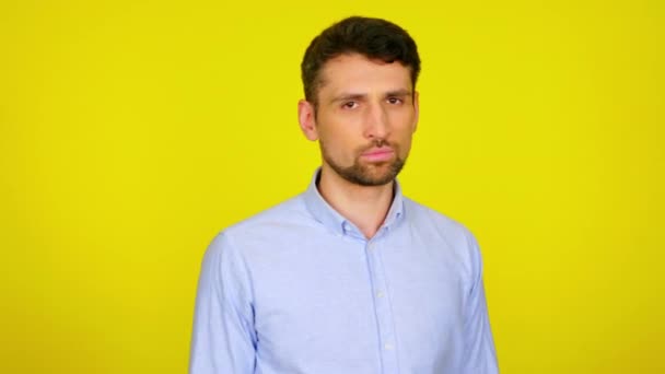 Muž se otočí ke kameře, zkříží ruce a potřese hlavou na žlutém pozadí — Stock video