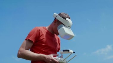 Adam bir kuadrokopteri uzaktan kumandayla kontrol ediyor.