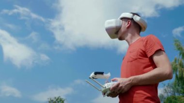 Adam bir kuadrokopteri uzaktan kumandayla kontrol ediyor.