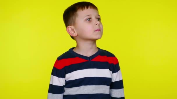 Verward kind jongen kijkt om zich heen en denkt wat te kiezen door het opheffen van de handen omhoog — Stockvideo