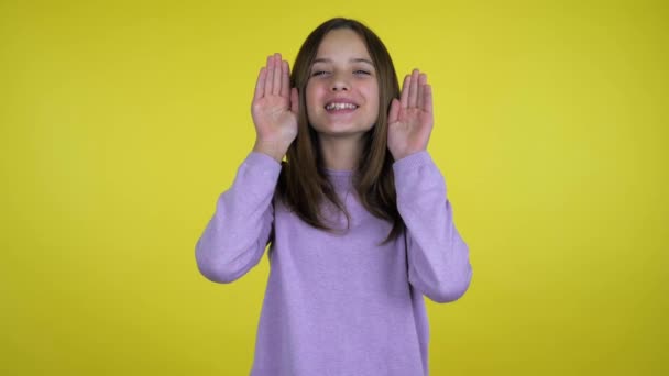 Teen ragazza raccoglie palme dal suo viso e sorride su uno sfondo giallo — Video Stock