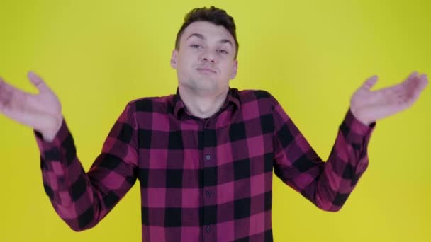 Ich weiß es nicht. Mann im rosa karierten Hemd hebt die Hände vor gelbem Hintergrund — Stockvideo