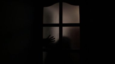 Bıçaklı bir adam gölgesi. Bir adamın ellerinde buzlu cam ile karanlık siluet