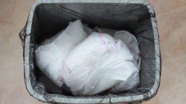 Bir yeni doğmuş bebek bezi. Evde çocuk bezi atma. Baba kullanılan bebek bezi çöp kutusuna atar.