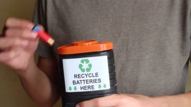 Tüm pilleri geri dönüşüm kapsayıcısı. Genç adam yerlerde kullanılmış pilleri içine belgili tanımlık kutu