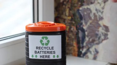 Pil toplama kutusu. Sıralama atık. Genç adam yerlerde kullanılmış pilleri içine belgili tanımlık kutu