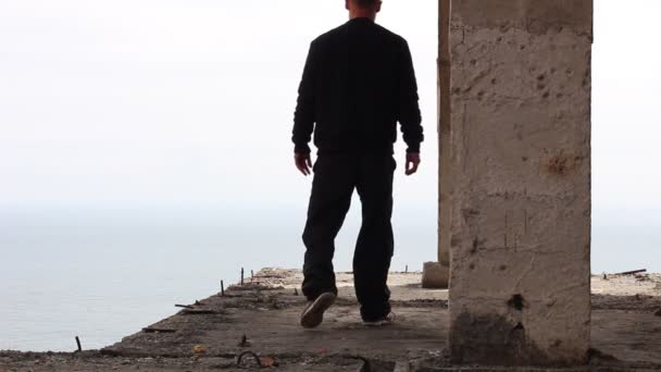 放棄された工事現場の男 男は背の高い建物の端に行く — ストック動画