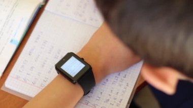 Genç Smartwatch aygıtla ders yapıyor. Teknoloji, software ve Gadget'ları sınıfta. Eğitim apps akıllı saatler için. Üçüncü taraf IP tasvir
