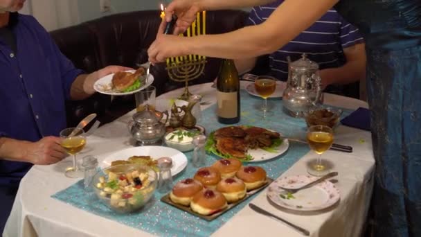 ハヌカは家族や友人と家でライトを灯します 光の祭典 ユダヤ人の休日の食事 伝統的なハヌカ料理 夕食を食べる家族 — ストック動画