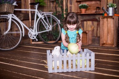 küçük kız lahana Paskalya süsleri bir arka plan üzerinde bir sepete koyar