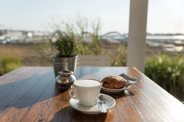 Breakfast of cappuccino and pastry at the beach — Stock Photo, Image