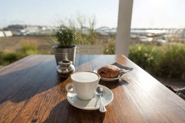 Frukost med cappuccino och bakverk på stranden — Stockfoto