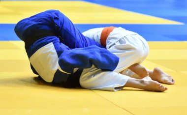 Kimonolu iki kız judoka tatamide yarışıyor.