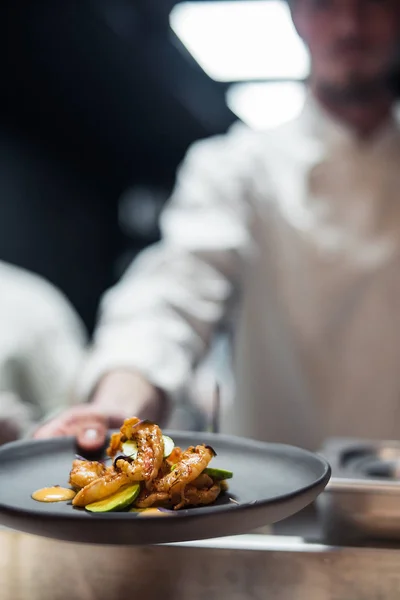 Ресторан шеф кухаря тримає страву з креветками та авокадо — стокове фото