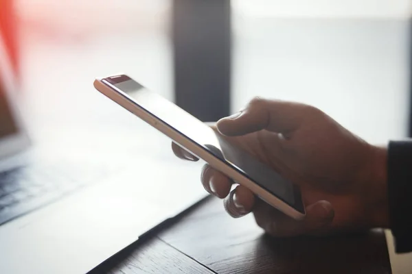 Ung man med tatuering håller mobiltelefon och arbetar på bärbar dator — Stockfoto