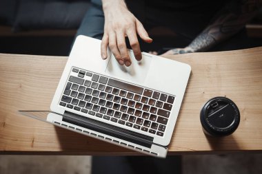 Genç adam üstünde laptop çalışma ve kahve içme.