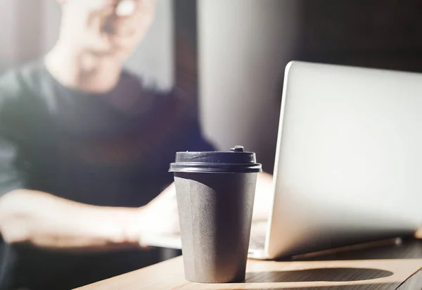 Молодий чоловік працює на ноутбуці і п'є каву . — стокове фото