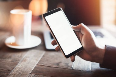 Holding cep telefonu ve içme sütlü kahve genç adam.