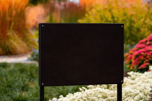 Cartelera negra en blanco con espacio vacío en el fondo del parque o del jardín. Tablero de lona para publicidad o mostrador de información. Primer plano —  Fotos de Stock