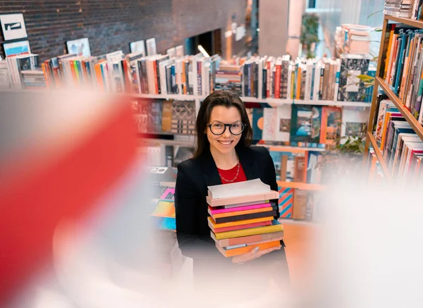 Fogyatékos nő, aki könyveket tart az egyik kezében a könyvtárban, vagy könyvesboltban és vigyorog. A teljes élet fogalma — Stock Fotó