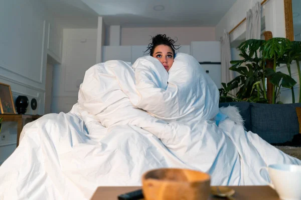 Woman Under Blanket Watching News über SARS Coronavirus, 2019-nCoV. Angst vor Pandemie. Stay Home Konzept. Nicht das Haus verlassen. Quarantäne. Lautes Image mit Körnern — Stockfoto