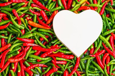 Beyaz kalp sıcak sevgi kavramı kırmızı ve yeşil biber üzerinde şeklinde