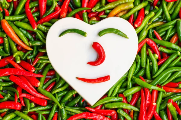Beyaz kalp sıcak sevgi kavramı kırmızı ve yeşil biber üzerinde şeklinde