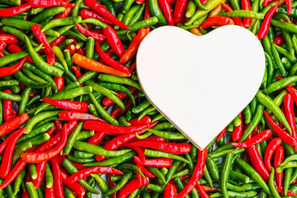 Beyaz kalp sıcak sevgi kavramı kırmızı ve yeşil biber üzerinde şeklinde