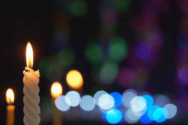 Candle lit in front of festive lights Christmas