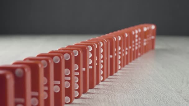 Effet domino - une série de dominos rouges tombant sur la chaîne sur une table en bois — Video