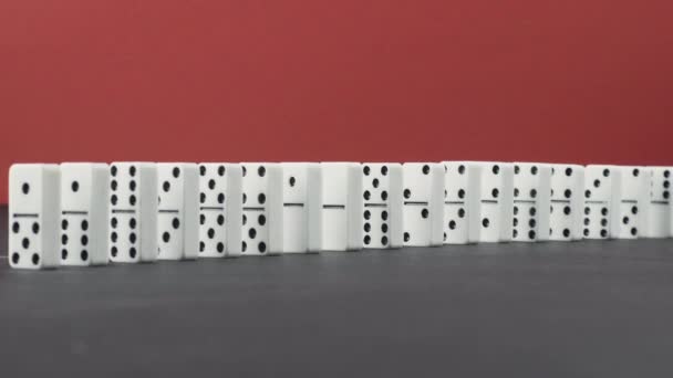 Dominoeffekt - en rad dominobrickor faller ner kedjan på röd bakgrund — Stockvideo