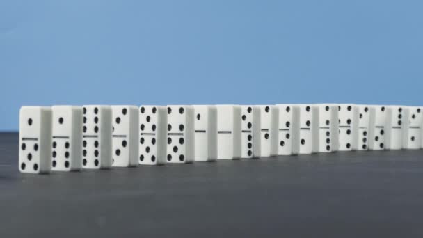 Domino etkisi - Domino zinciri mavi zemin üzerine düşen bir dizi — Stok video
