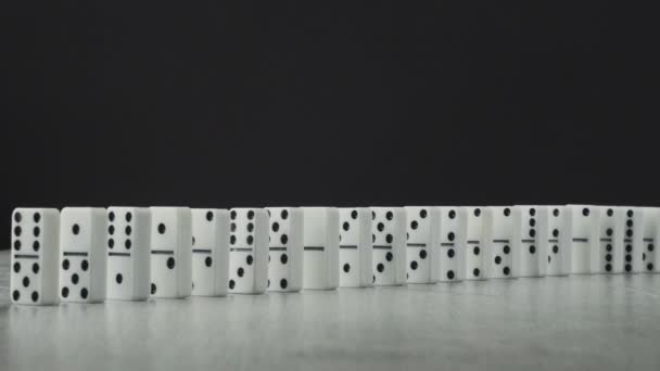 Domino effect - a series of dominoes falling down the chain on wooden table with black background — Stock Video