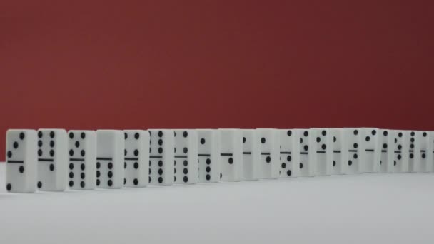 Efeito dominó - uma série de dominós caindo na cadeia sobre fundo vermelho — Vídeo de Stock